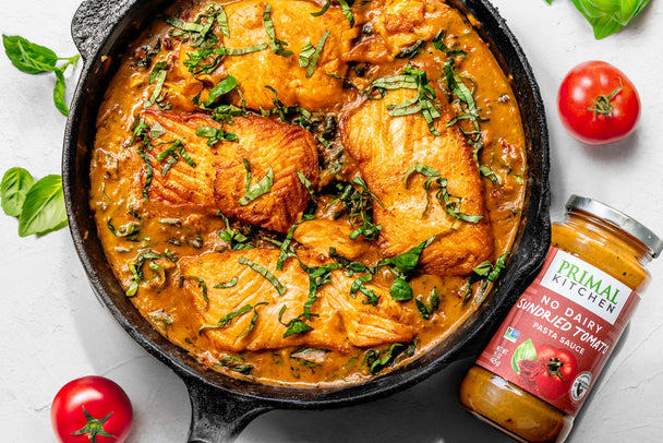 Salmon filets with sundried tomato sauce in a cast iron skillet.