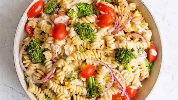 A bowl of ranch pasta salad with fresh vegetables and Primal Kitchen No-Dairy Ranch.