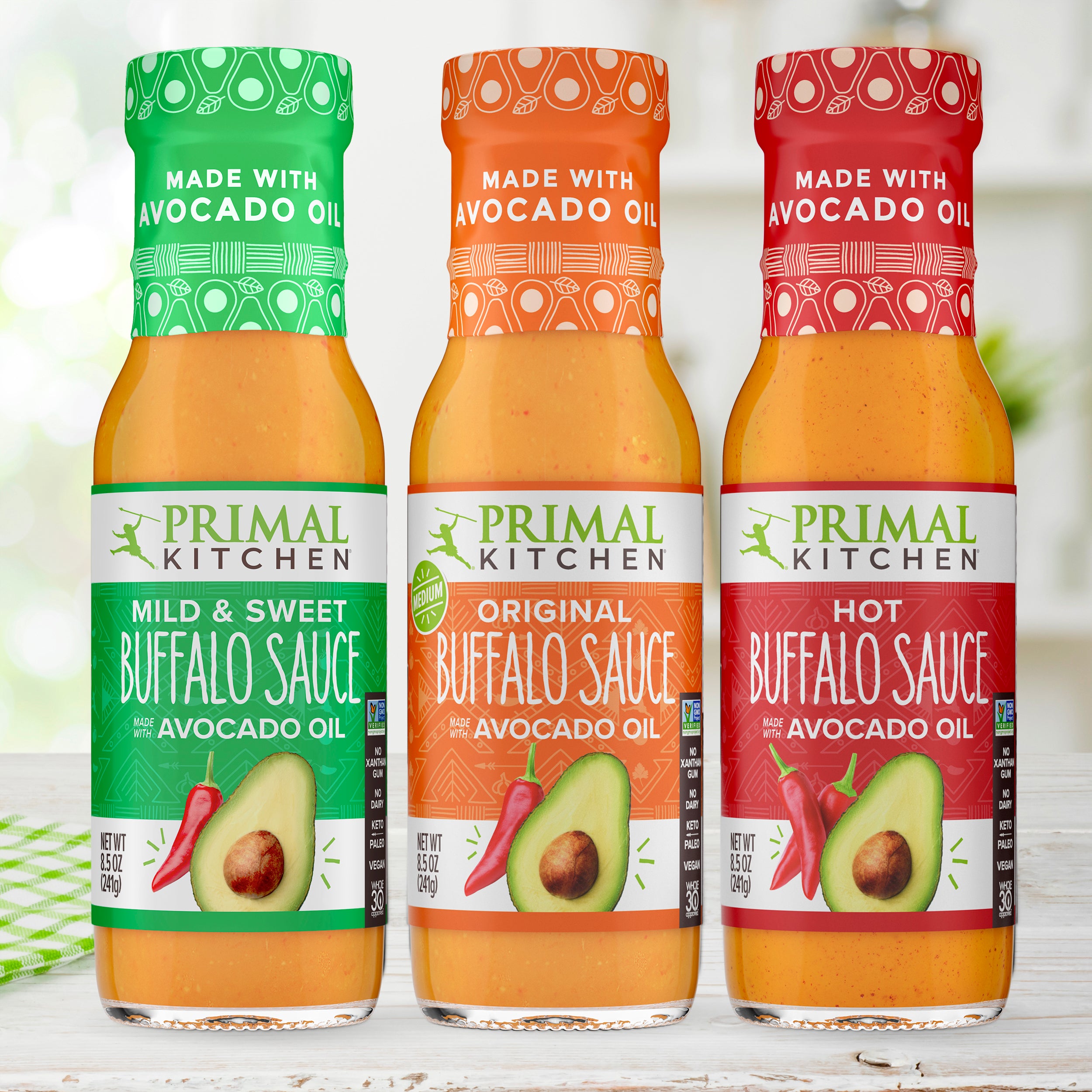 Three bottles of Primal Kitchen Mild and Sweet Buffalo Sauce, Original Buffalo Sauce made with Avocado Oil, and Hot Buffalo Sauce