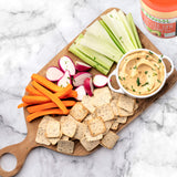Snack spread of carrots, crackers, radishes, celery and Primal Kitchen Chipotle Lime Mayo in a white car on a wooden board next to a jar of Primal Kitchen Chipotle Lime Mayo.