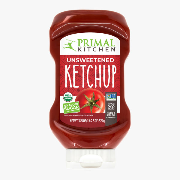 A Squeeze Bottle of Primal Kitchen Unsweetened Ketchup with No Added Sugar with a red label on a light grey background.