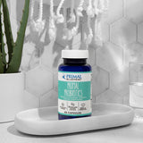 A blue bottle of Primal Blueprint Primal Probiotics on a white tray against a white tile background with an aloe pant next to it.