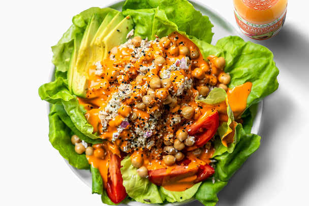 Chickpea tuna salad on a bed of lettuce with Primal Kitchen buffalo sauce poured on top