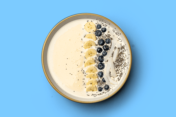 A vanilla coconut smoothie bowl made with Primal Kitchen Collagen powder, topped with blueberry and banana.