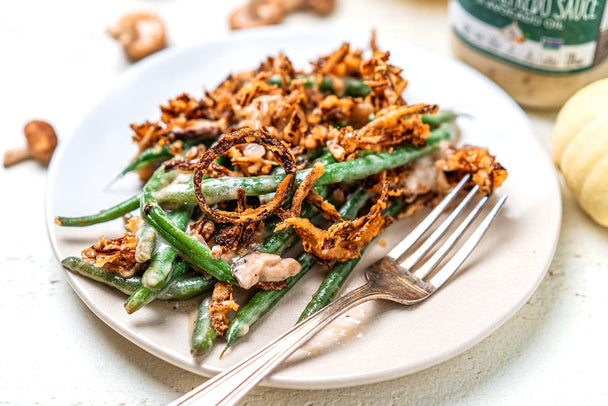 A white plate with a serving of green bean casserole and a fork.