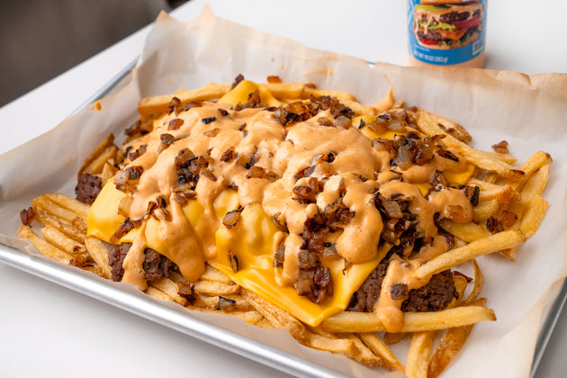 A tray of secret menu fries next to a bottle of Primal Kitchen Special Sauce.