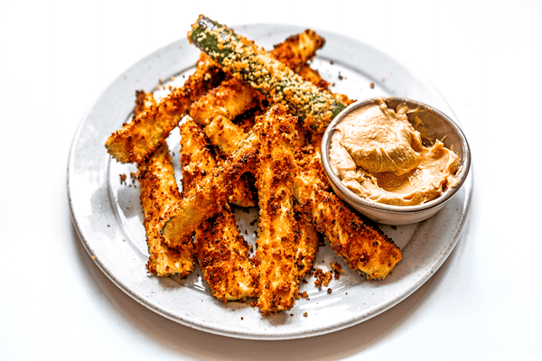 A plate of zucchini sticks with a ramekin of chipotle lime mayo for dipping.