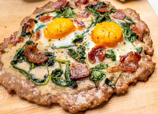 A meatza lays cooked on a wooden cutting board.
