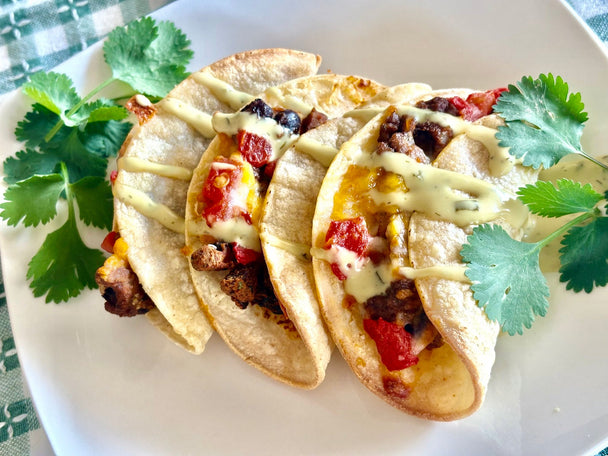 3 street tacos on a white plate garnished with fresh cilantro