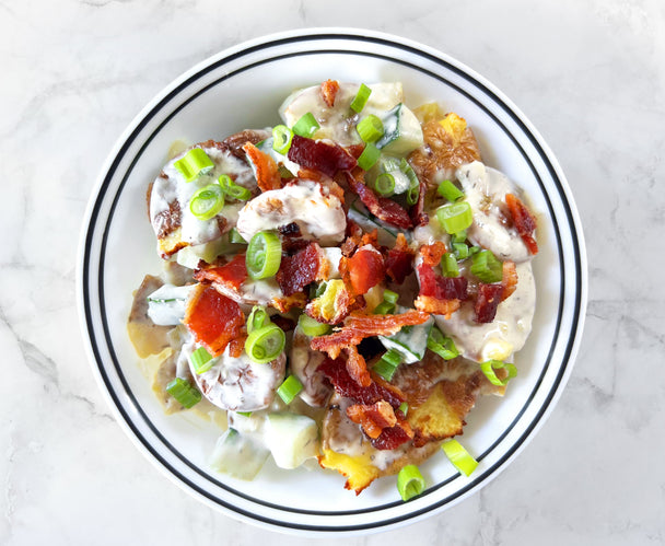 Overhead view of a bowl of ranch smashed potato salad topped with bacon and green onions. 