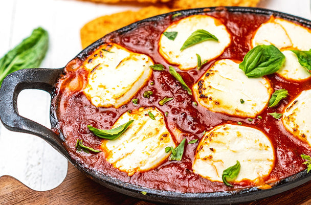 Baked marinara dip with goat cheese in a cast iron skillet.