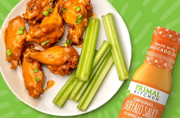 Plate of buffalo wings with celery sticks and Primal Kitchen Buffalo Sauce