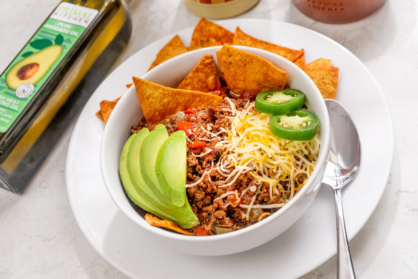 Chili recipe in a white bowl with a silver spoon. Primal Kitchen Pure Avocado Oil in the background.