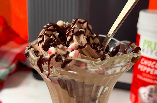 Close up on dish of chocolate ice cream topped with crushed candy canes and chocolate syrup.