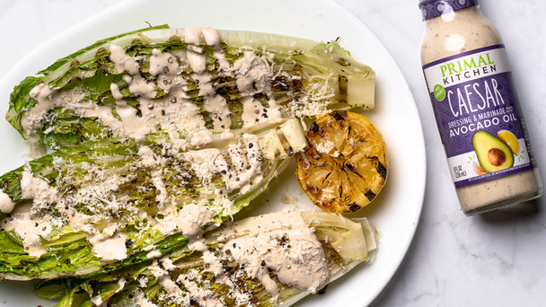 A plate of grilled romaine salad with Primal Kitchen Caesar Dressing.