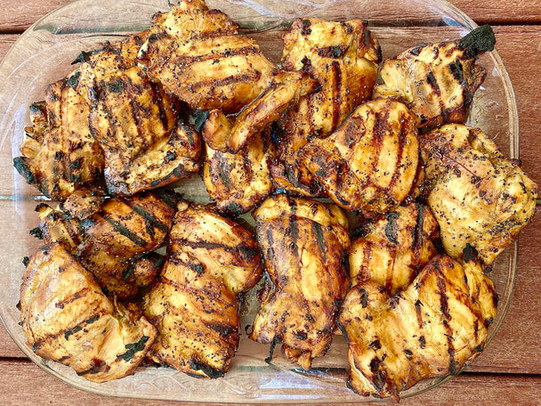 Platter of grilled chicken thighs with grill marks.