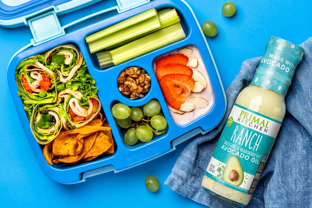 Bento box with turkey pinwheel sandwiches, assorted sides, and Primal Kitchen Ranch Dressing