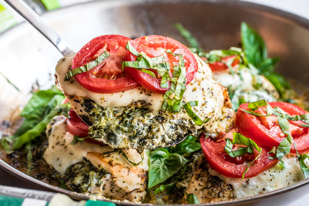 Pesto Mayo and Mayo lay next to a bowl with spinach stuffed christmas breast in it.