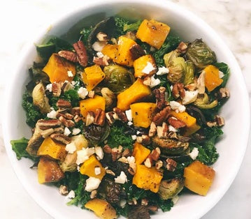 Butternut squash salad with kale and pecans in a white bowl. 