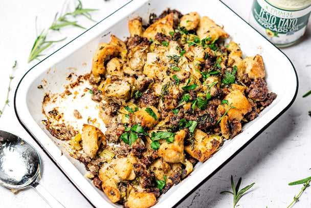 Gluten-Free Stuffing with Italian Sausage in a white casserole dish next to Primal Kitchen Pesto Mayo