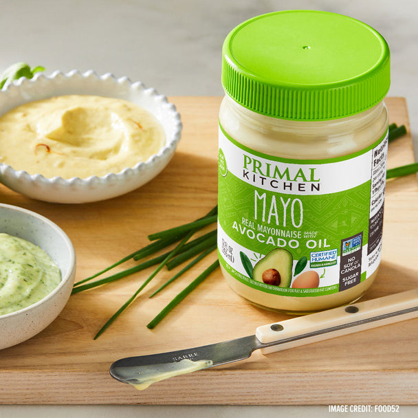 A jar of Primal Kitchen Mayo on a cutting board with a knife and mayo in bowls.