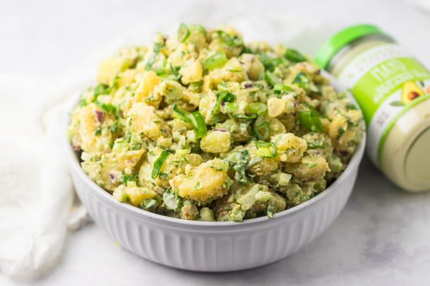 A bowl of creamy potato salad next to a jar of Primal Kitchen Mayo. 
