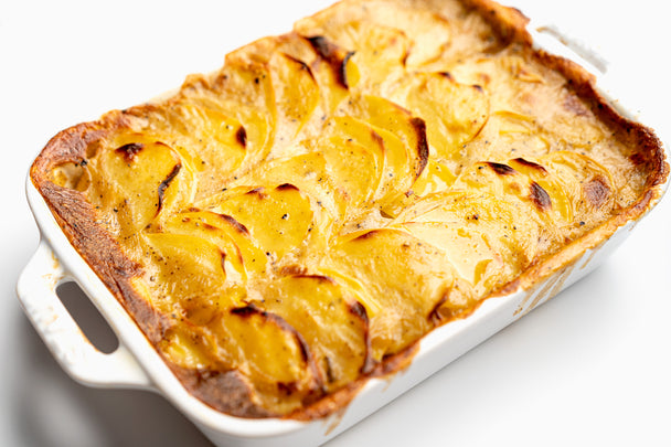Baked and browned vegan scalloped potatoes in a large white casserole dish