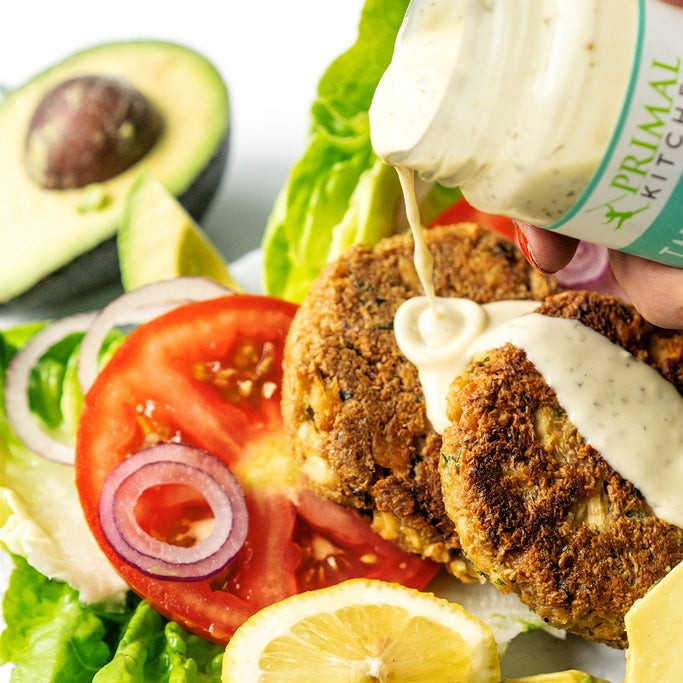 Tartar sauce pouring over salmon cakes