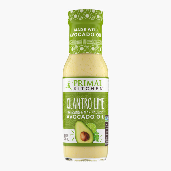 A bottle of Primal Kitchen Cilantro Lime Dressing and Marinade made with avocado oil, with a green label, on a light grey background.