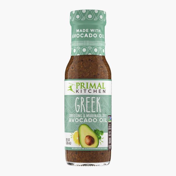 A bottle of Primal Kitchen Greek Dressing and Marinade made with avocado oil, with a light teal label, on a light grey background.