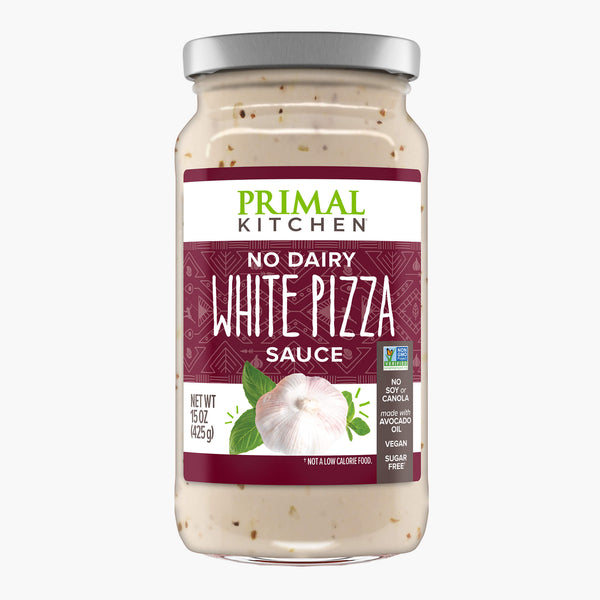 A jar of Primal Kitchen No Dairy White Pizza Sauce made made with avocado oil,  with a wine colored label, on a light grey background.