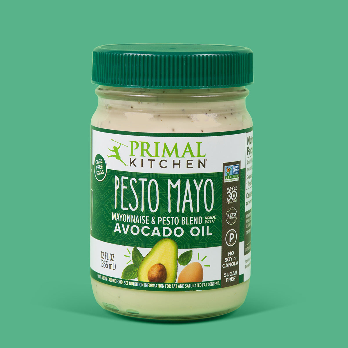 A jar of Primal Kitchen Pesto Mayo made with Avocado Oil with a dark green label and lid on a green background.