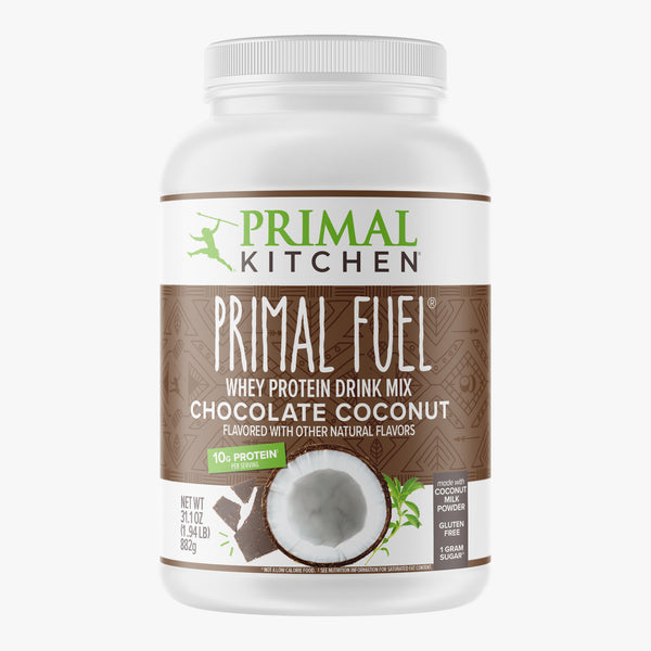 A canister of Primal Kitchen Primal Fuel, a Chocolate Coconut Whey protein drink mix with a brown and white on a light grey background.