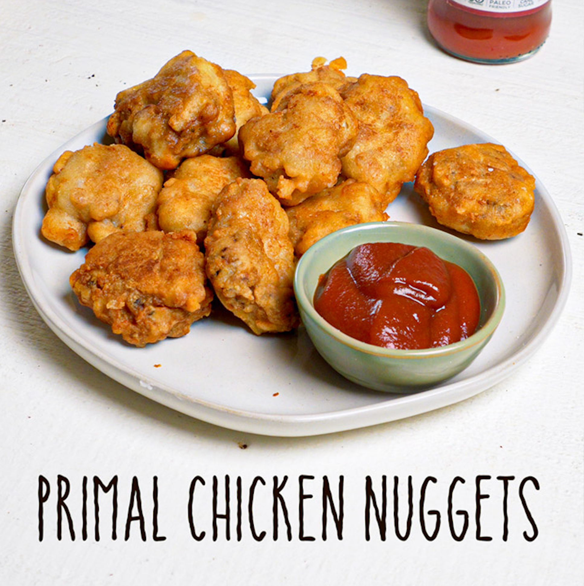 Primal Chicken Nuggets on a plate with a small dish of Primal Kitchen Organic & Unsweetened Ketchup
