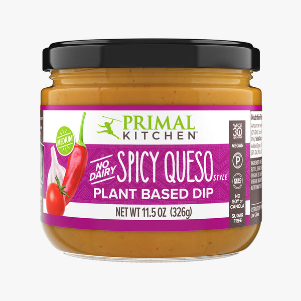 Front of a jar of Primal Kitchen Vegan No Dairy Spicy Queso Style Plant Based Dip with a dark purple label on a light grey background.