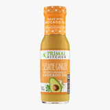 A bottle of Primal Kitchen Sesame Ginger Dressing and Marinade made with avocado oil, with an orange-yellow label, on a light grey background.