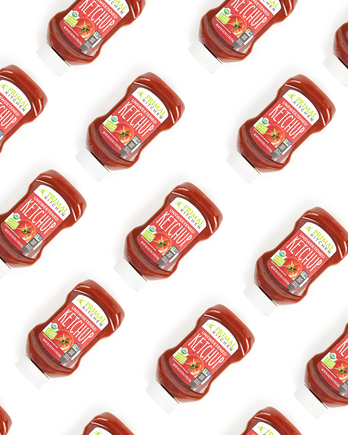 Staggered bottles of Primal Kitchen Unsweetened Squeeze Ketchup on a white background