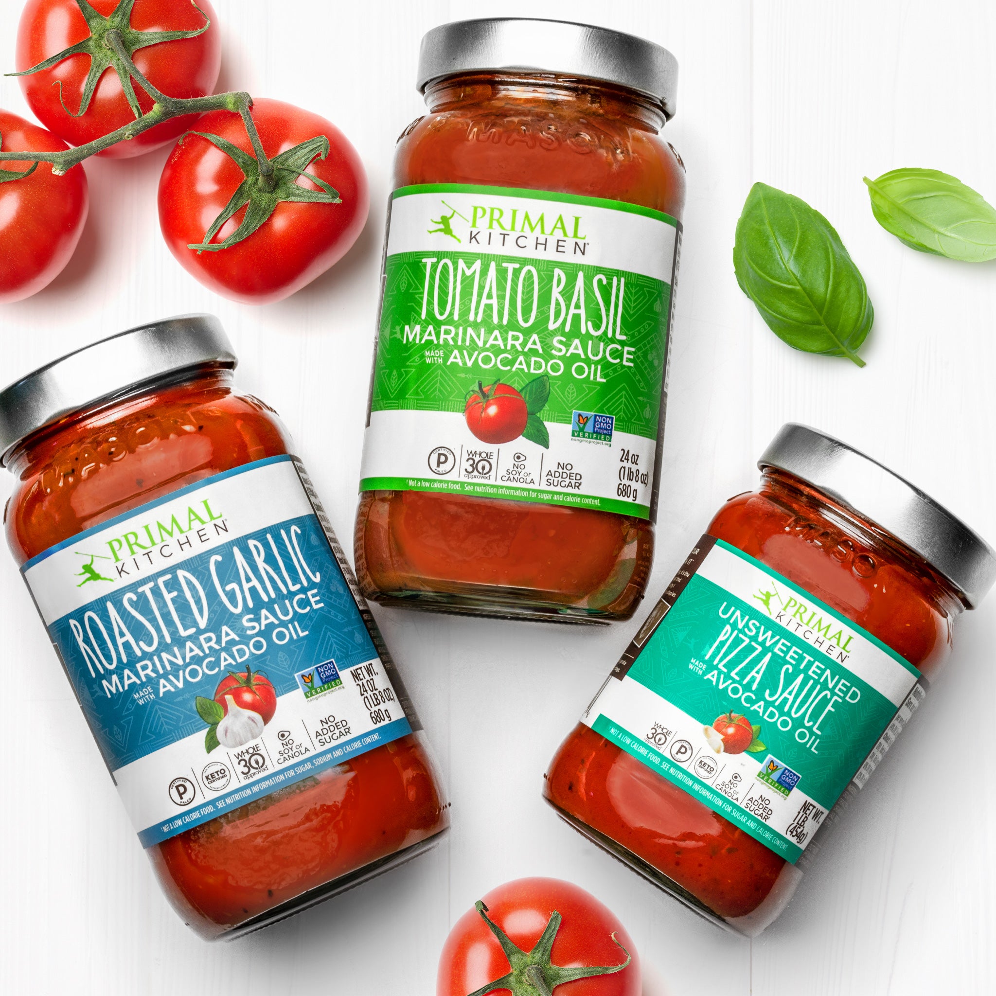 Jars of Primal Kitchen Roasted Garlic Marinara Tomato Sauce, Primal Kitchen Tomato Basil Marinara Pasta Sauce, and Primal Kitchen Unsweetened Red Pizza Sauce Made with Avocado Oil on a light grey background.